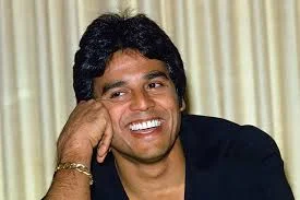 Erik Estrada posing in front of a motorcycle, representing his CHiPs role and net worth journey